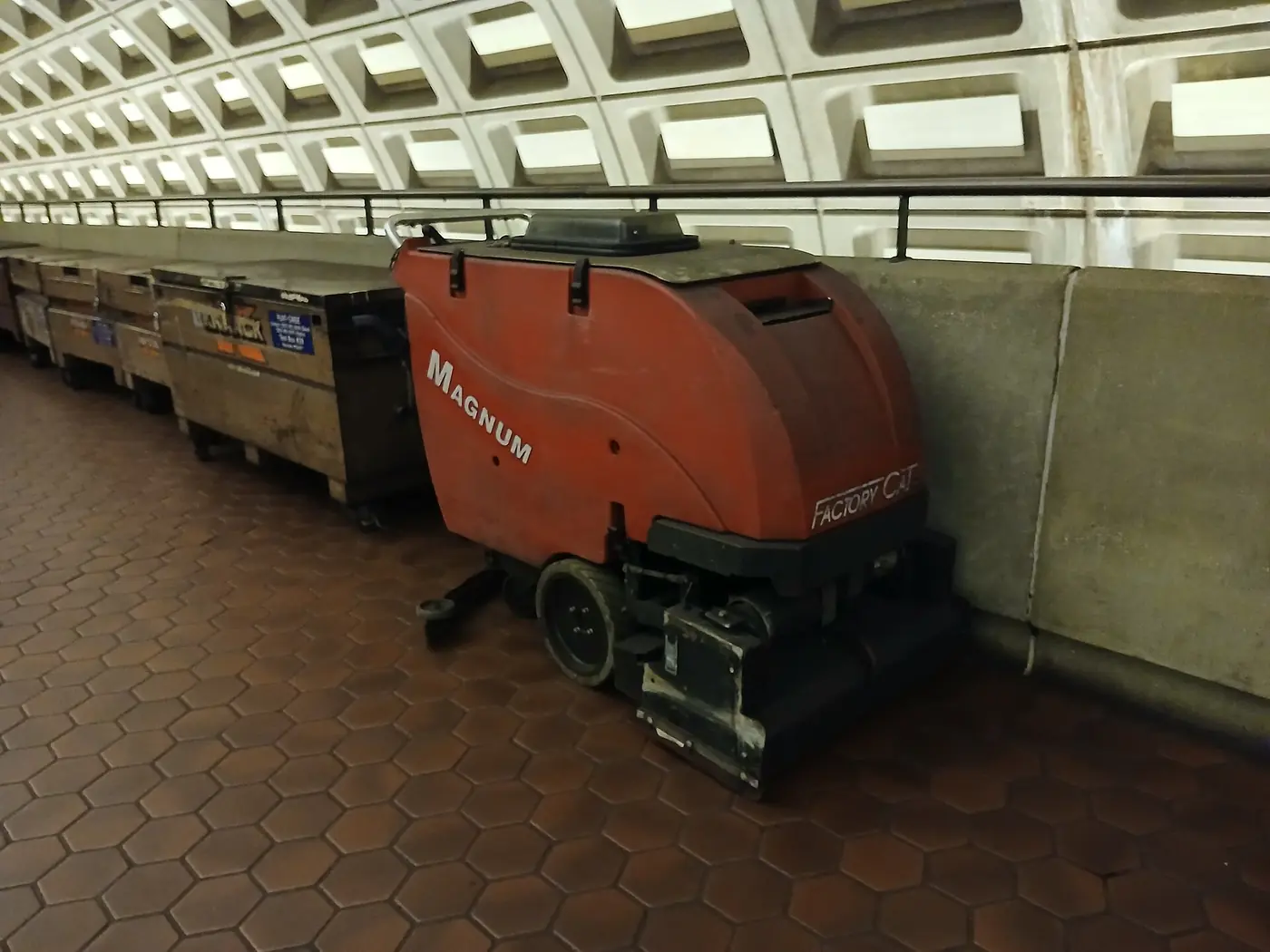 Autolaveuse rouge garée le long d'un quai de métro carrelé