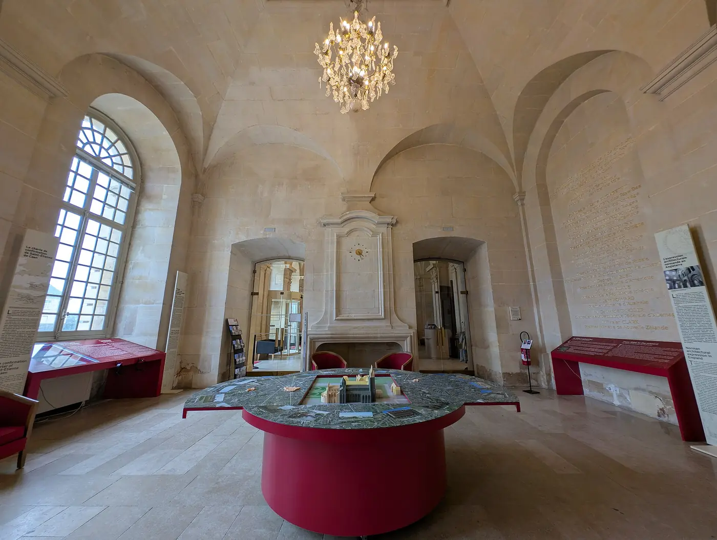 Salle voûtée de l'abbaye aux Hommes à Caen, avec un lustre et une table ronde rouge